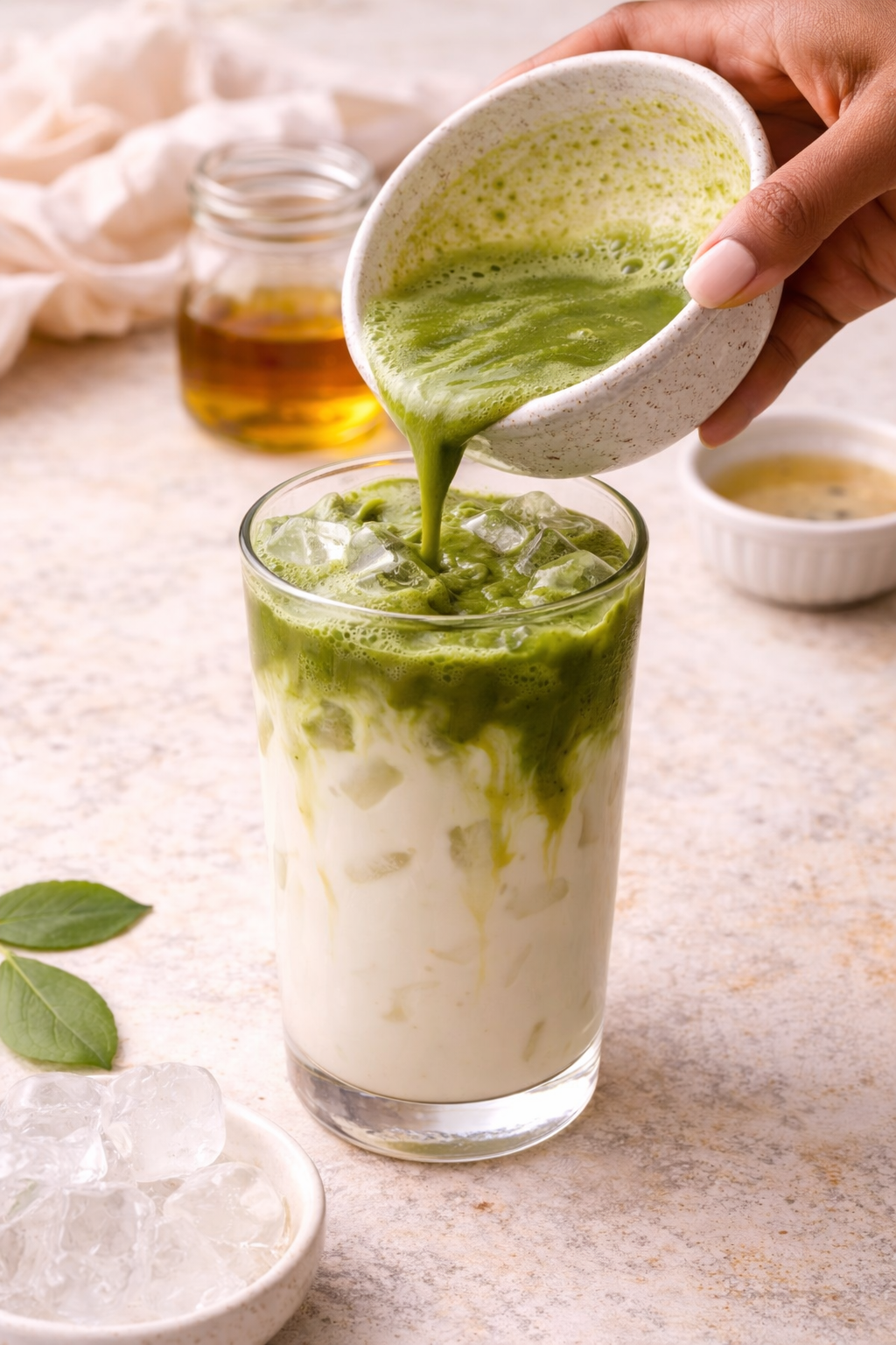 Pouring matcha over milk to create layered iced latte